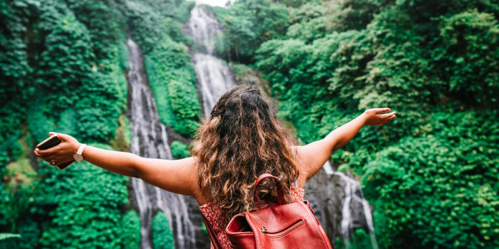 Solo Explorer Admiring Waterfall in a Dense Forest